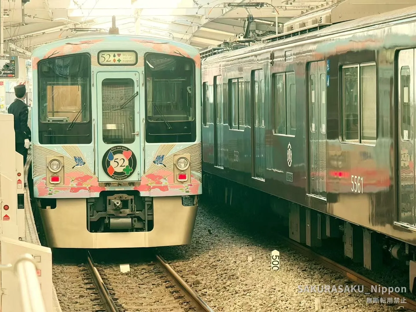 The 52 Seats of Happiness train at the platform, its "fifty-two seats of happiness" headmark beside an ordinary commuter train