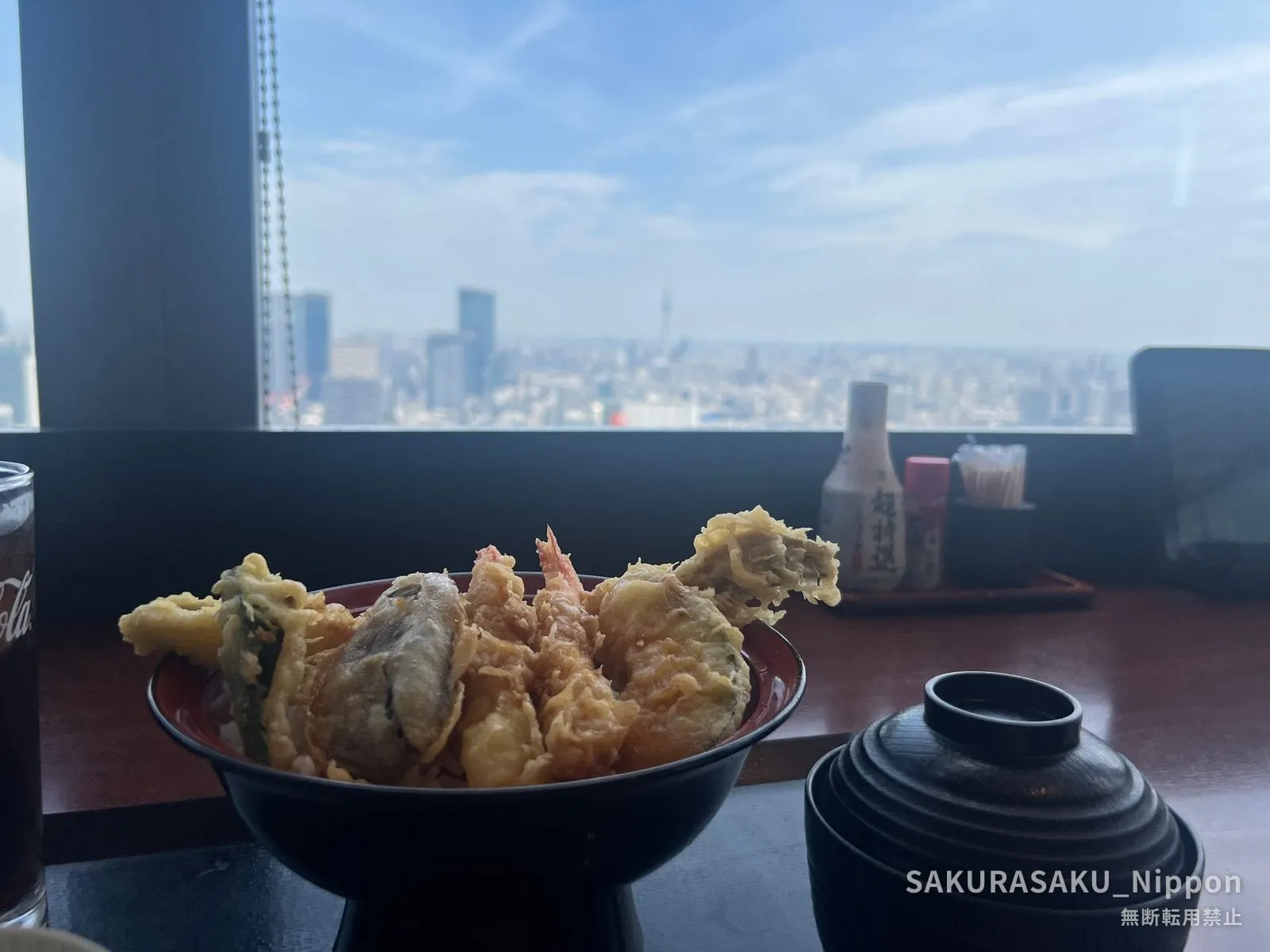 A tempura bowl on the table, with the Tokyo skyline and Skytree through the window