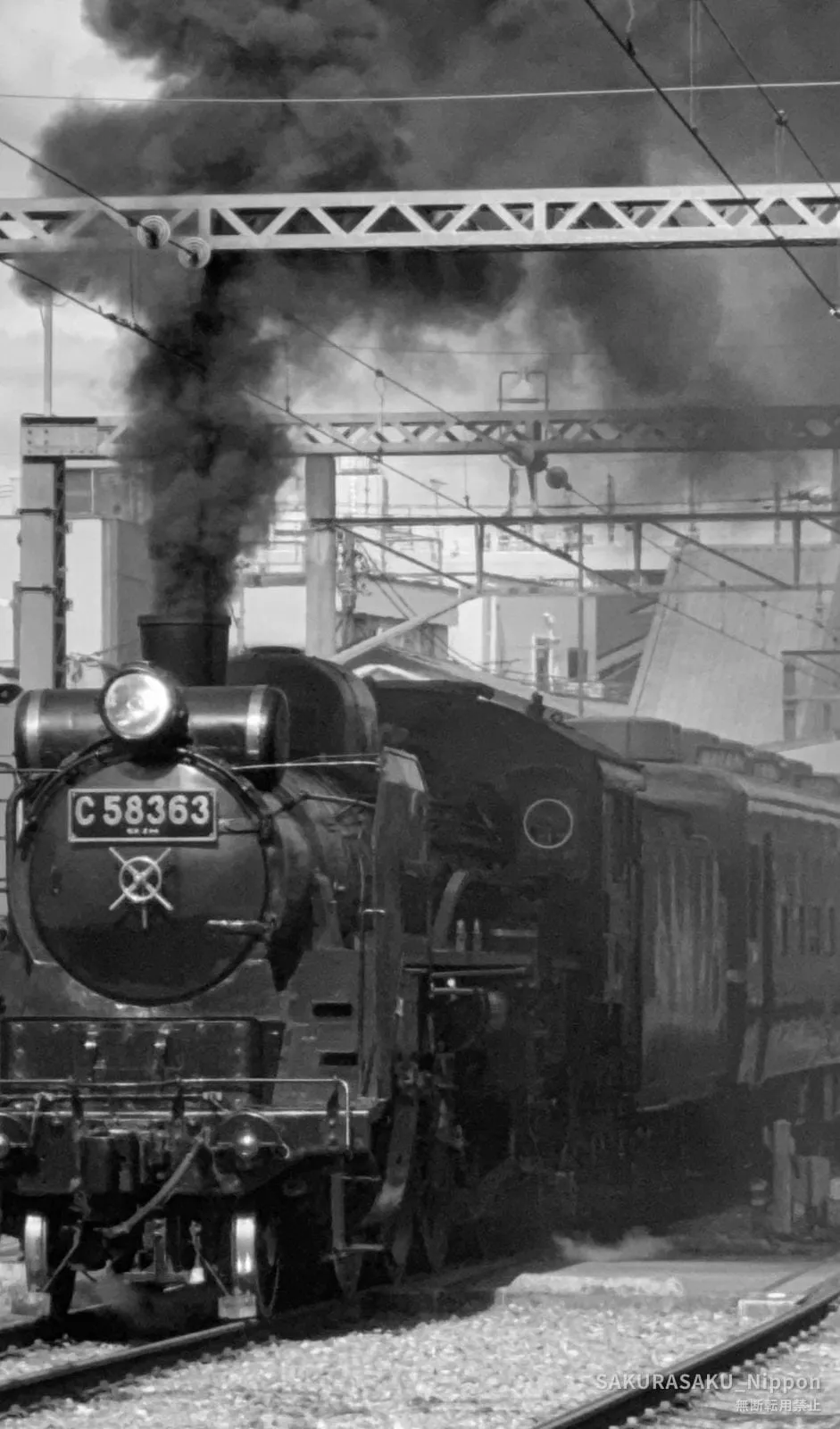 The locomotive C58 363 head-on in monochrome, black smoke standing straight up above the chimney