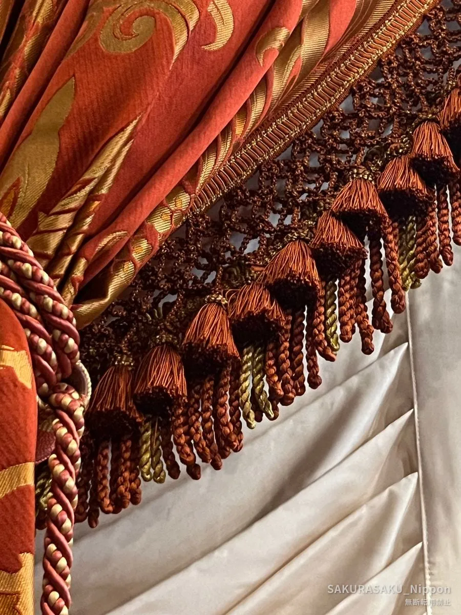 Close-up of a gold and orange curtain with heavy silk tassels