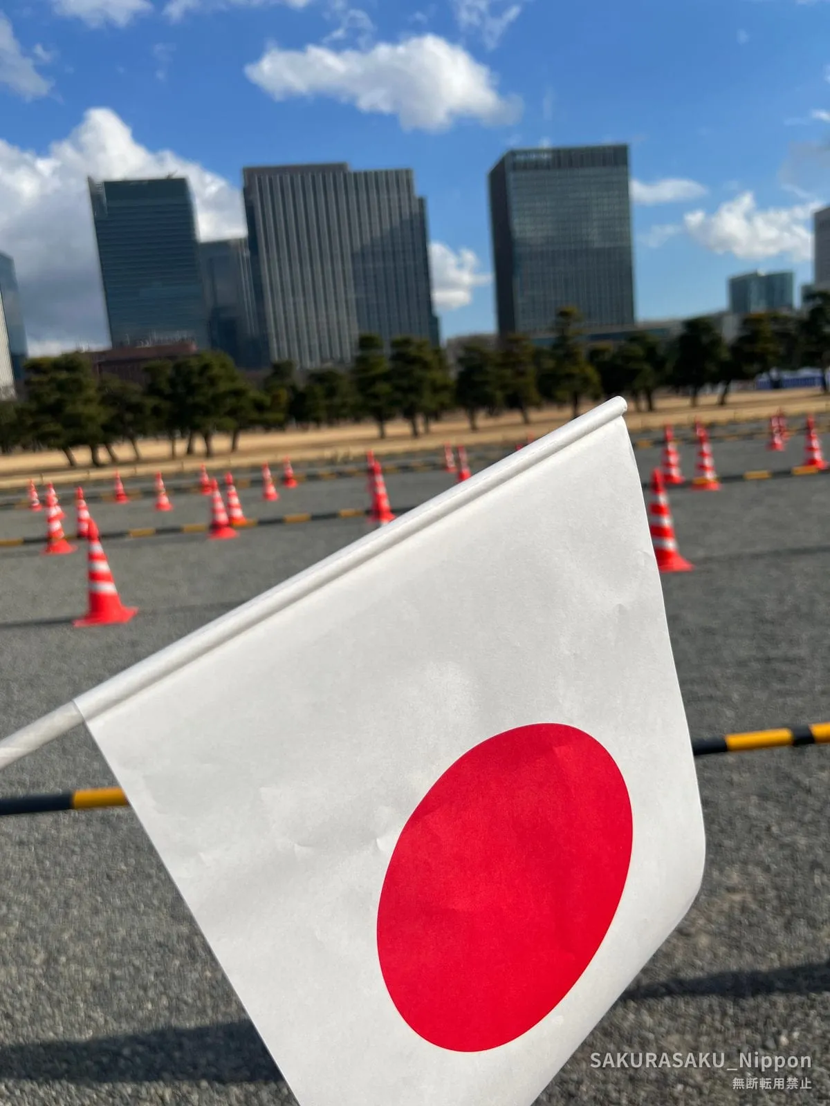 A paper flag against the Marunouchi skyline, on the palace plaza