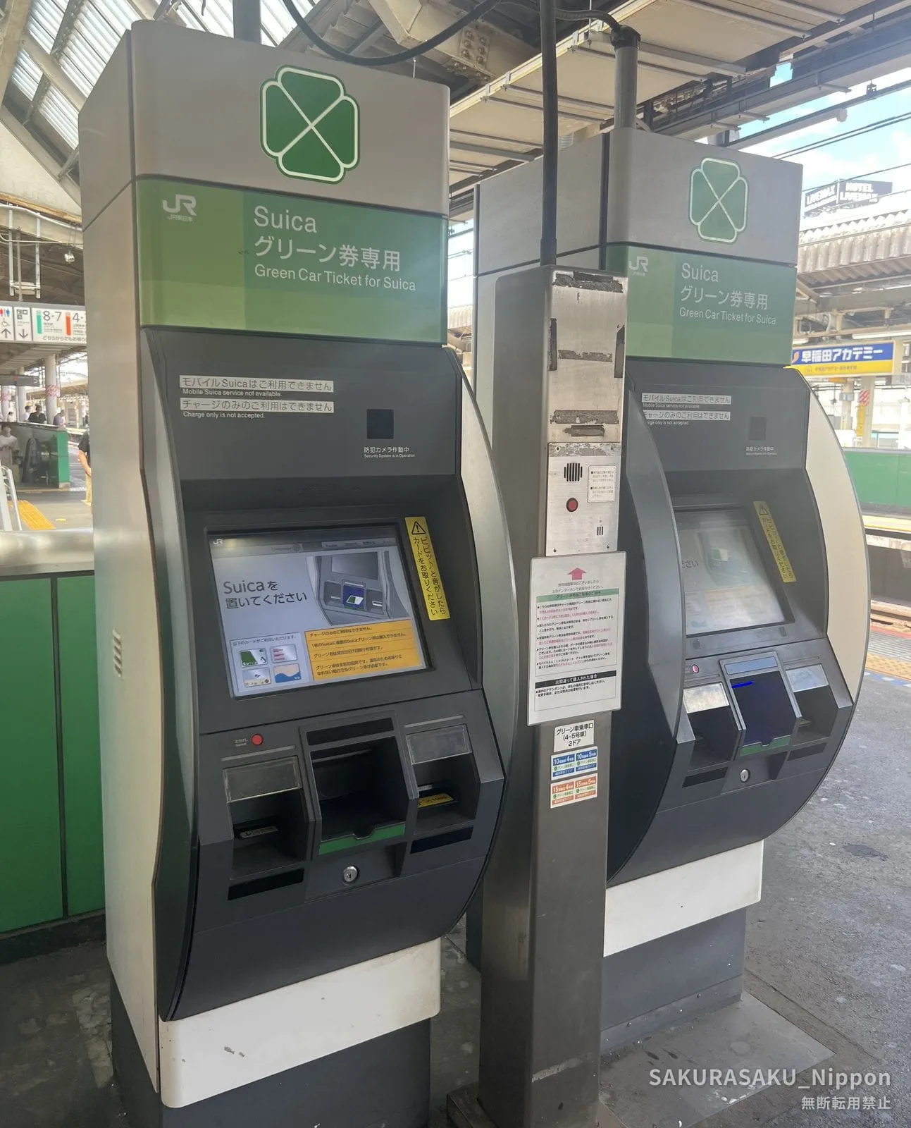 Two green Suica Green Car ticket machines on a platform