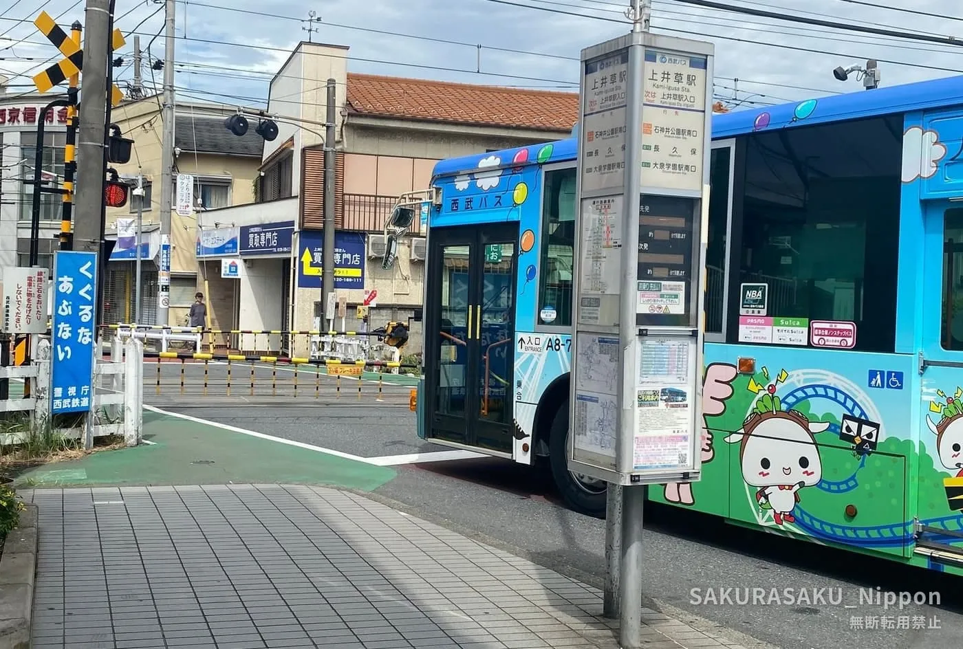The south exit of Kami-Igusa Station, with its bus stop and the level crossing just beside it
