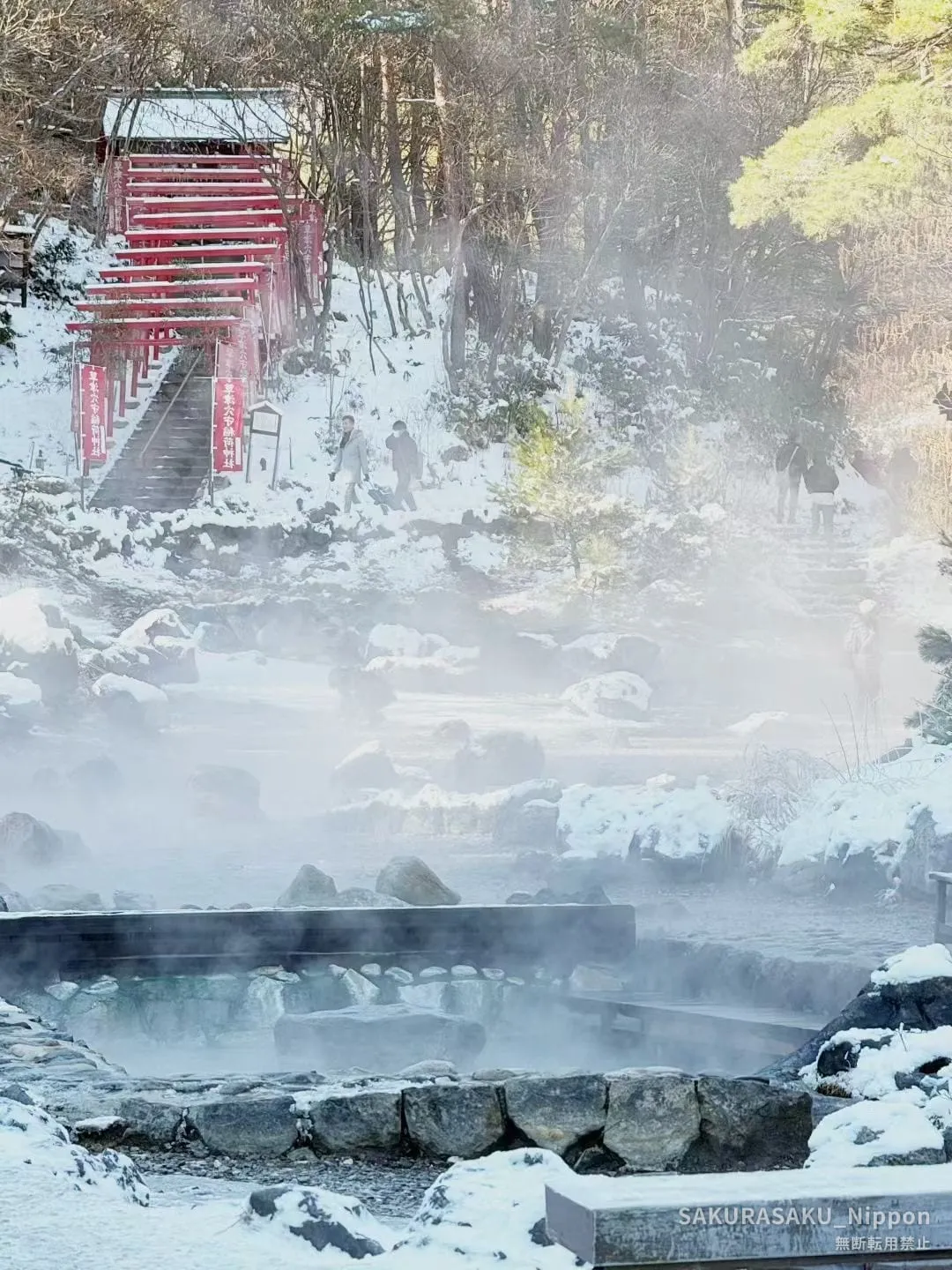 Snow, red torii gates, and steaming water at Sainokawara Park in Kusatsu