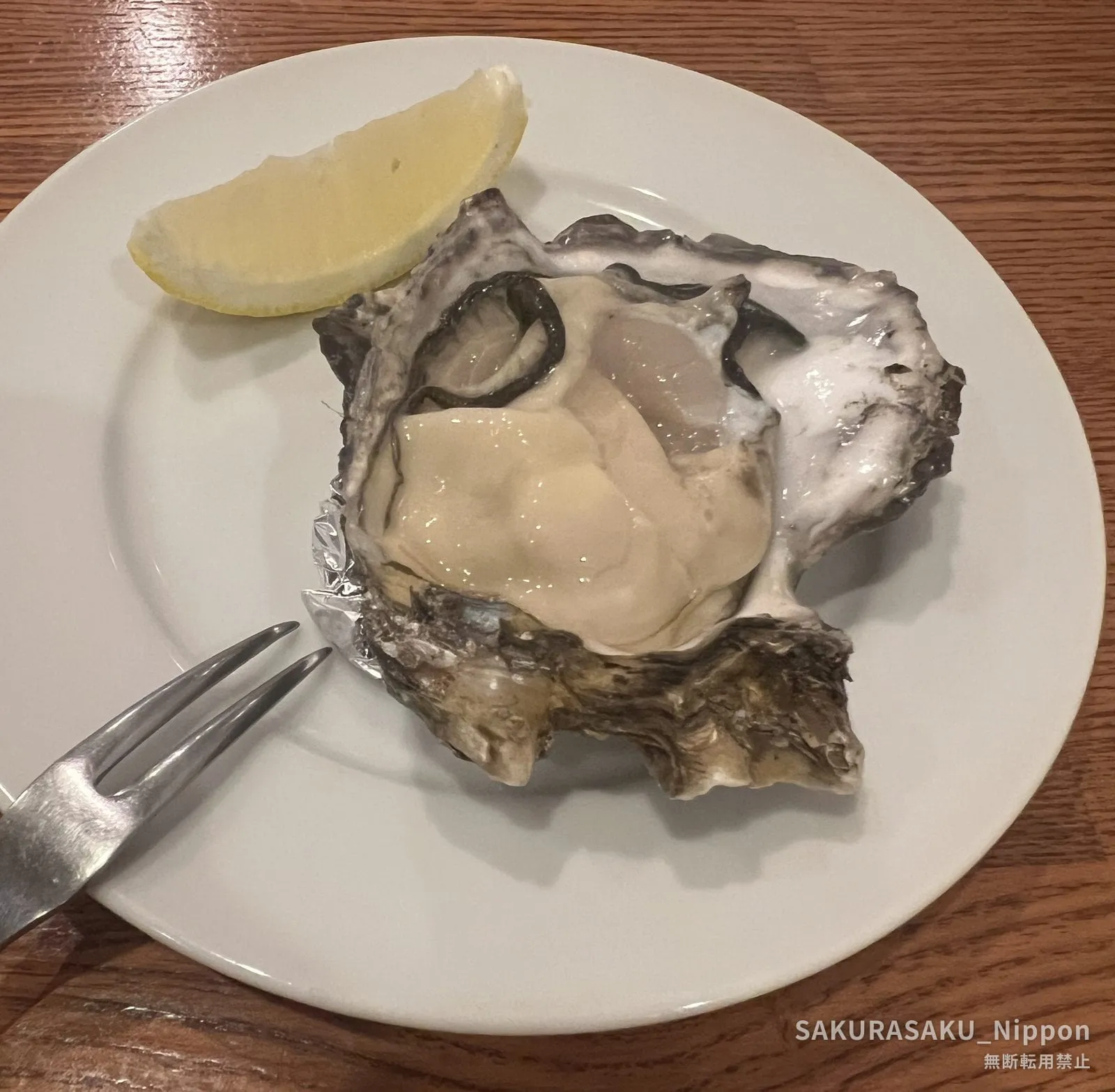 A single fresh oyster on the half shell with a wedge of lemon