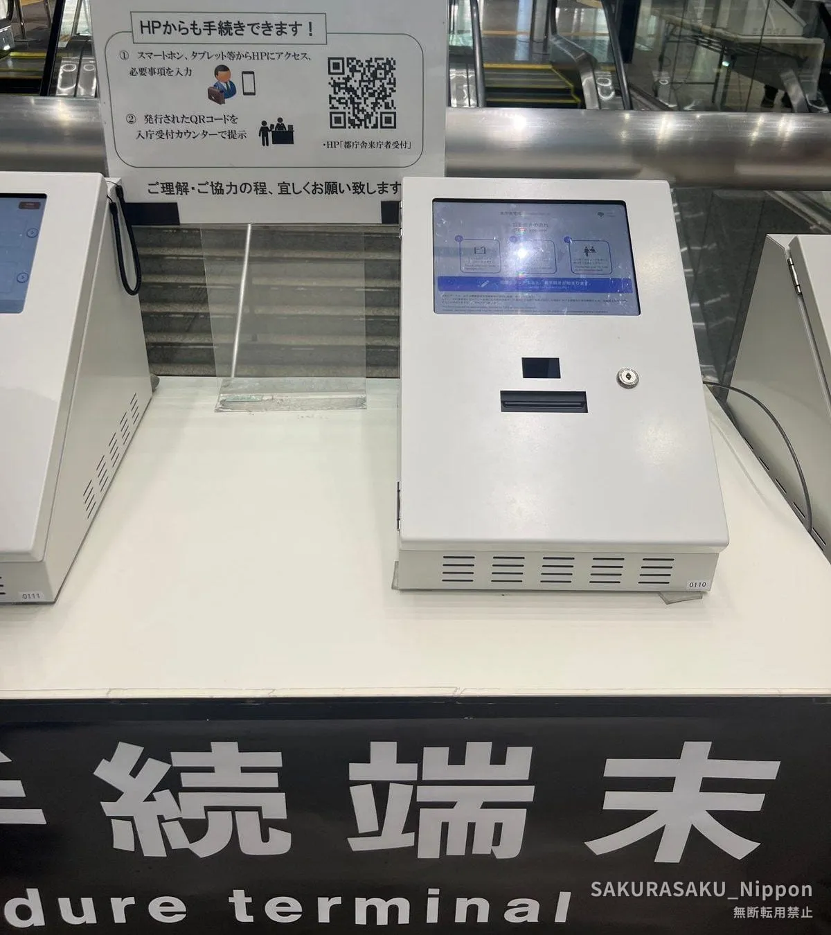 A visitor registration terminal in the Tokyo Metropolitan Government Building, with a sign explaining that the procedure can also be done online