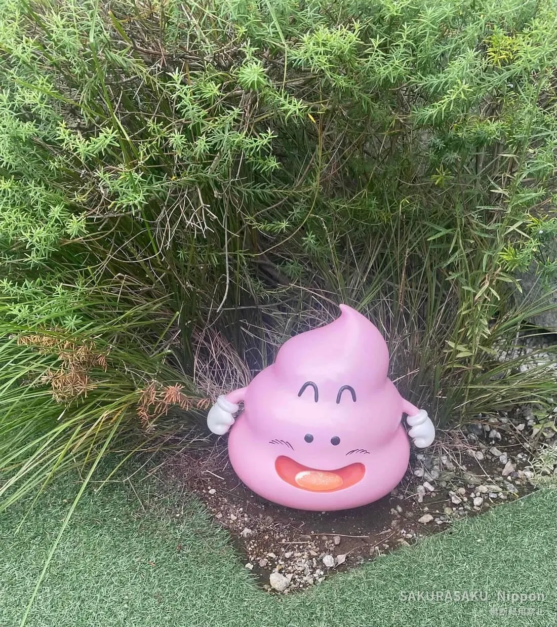 The grinning pink poop from Dr. Slump hiding in the bushes