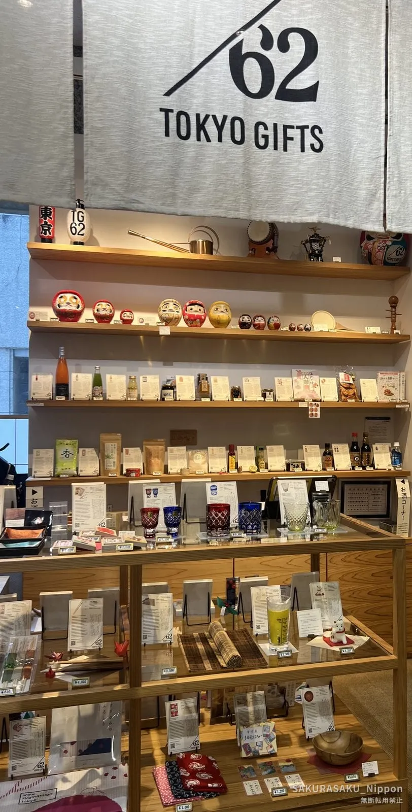 Inside TOKYO GIFTS 62: daruma dolls, kokeshi, glassware and condiments on wooden shelves